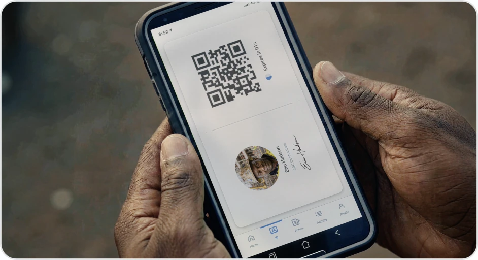 A worker holding a phone showing their Sitemate ID card and QR code